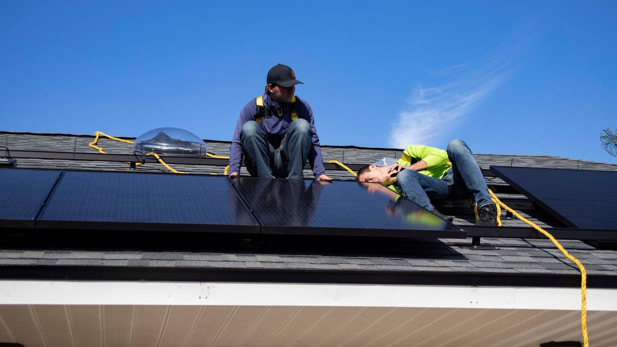 Installateurs plaatsen zonnepanelen op het dak van een woning